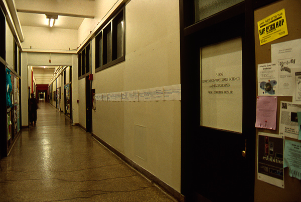 War protest sheets with quotes from news agencies pasted across typical white corridor wall at MIT