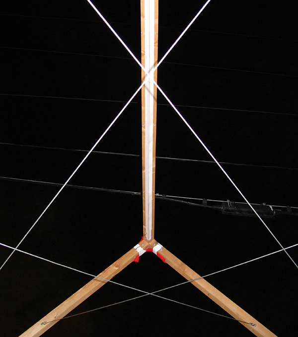 Assembly study showing cedar beams and criss-crossing steel cables against night sky