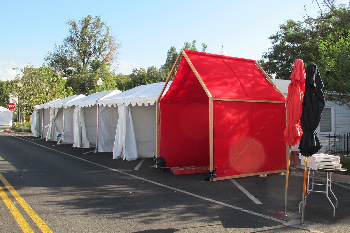 Red felt and cedar, mobile, temporary pavilion installation next to typical white vinyl art booths