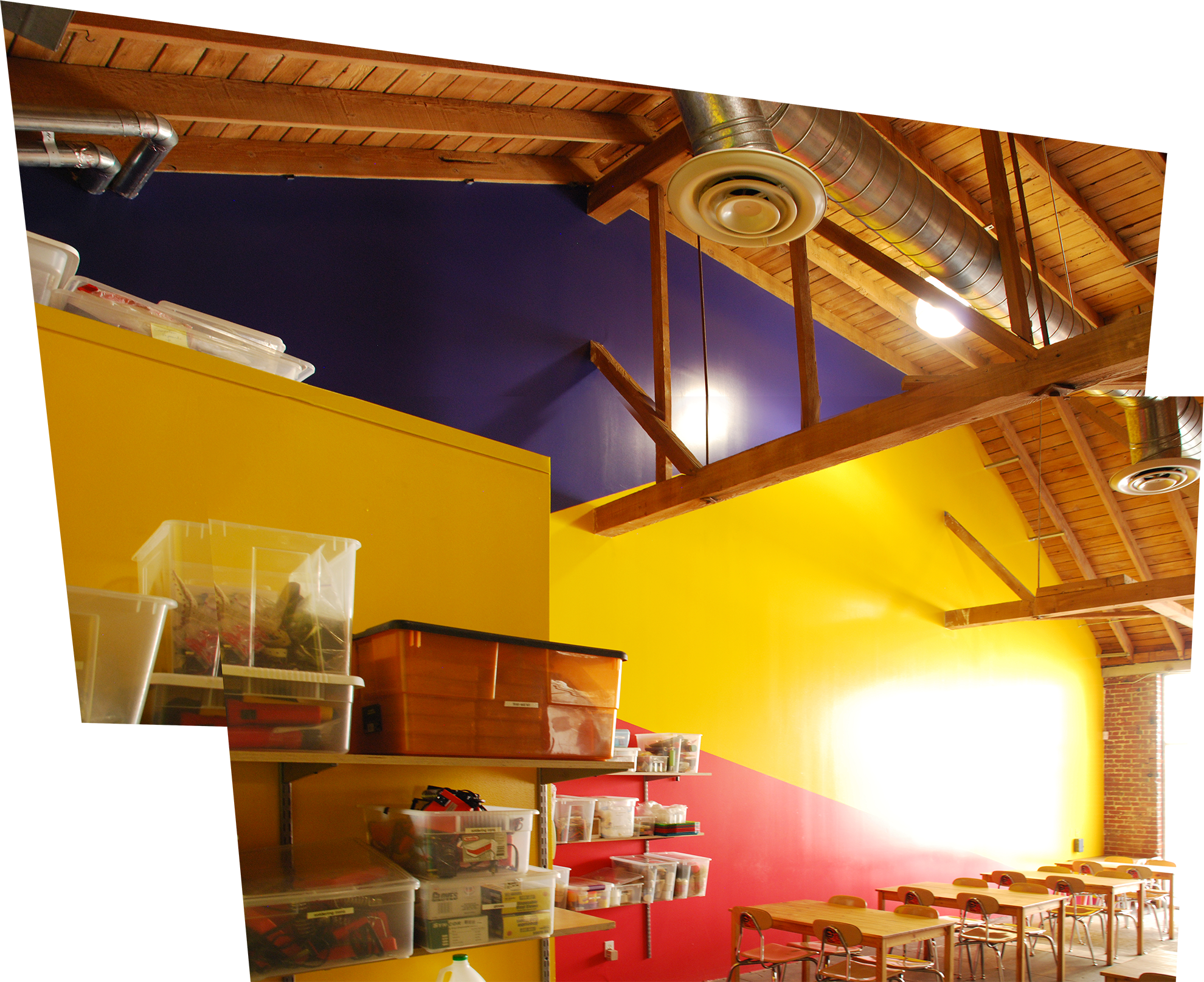 A large interior wall, double height, is painted in triangulated areas, with blue at the top, yellow in the center, which gets bigger toward the light in the front, and reddish-magenta at the bottom.