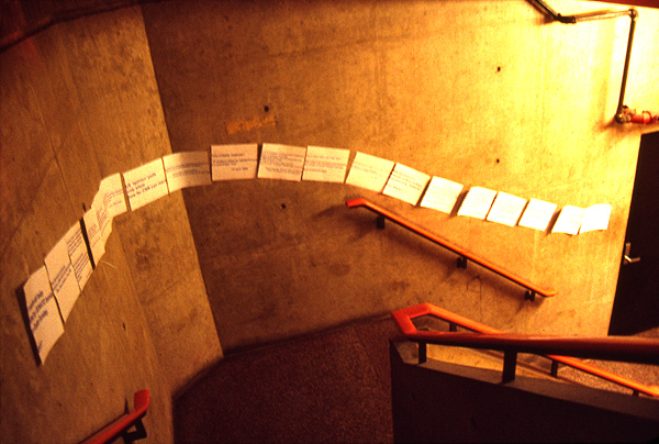 War protest sheets with quotes from news agencies pasted across concrete stair wall at MIT